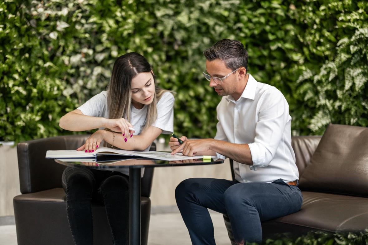 Zwei Personen sitzen am Tisch und schauen auf Dokumente