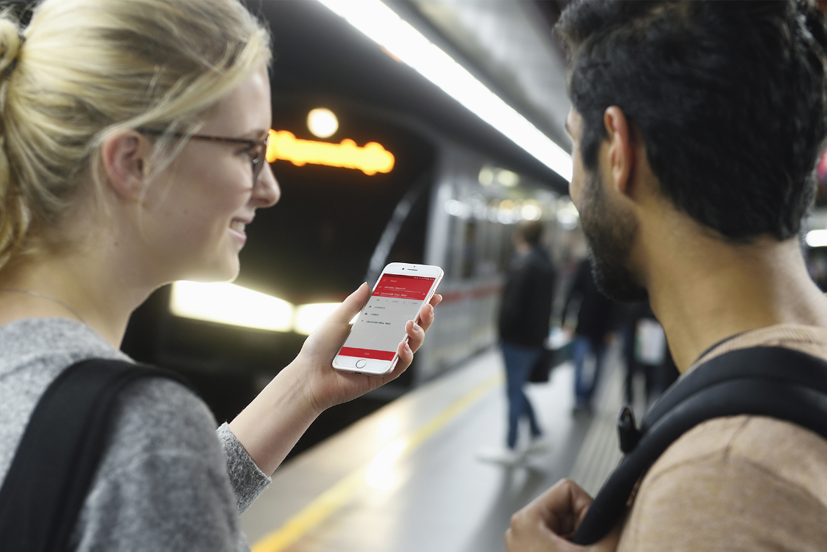 Zwei Personen stehen vor einer U-Bahn, die Person link hält ein Smartphone in der Hand